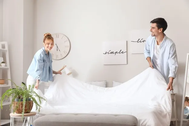 Man and Woman Making Up a Spare Bed For Guests