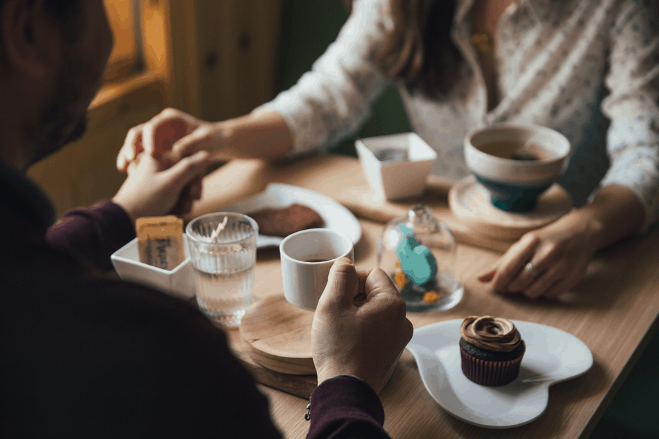 A Couple Holding Hands During Dinner